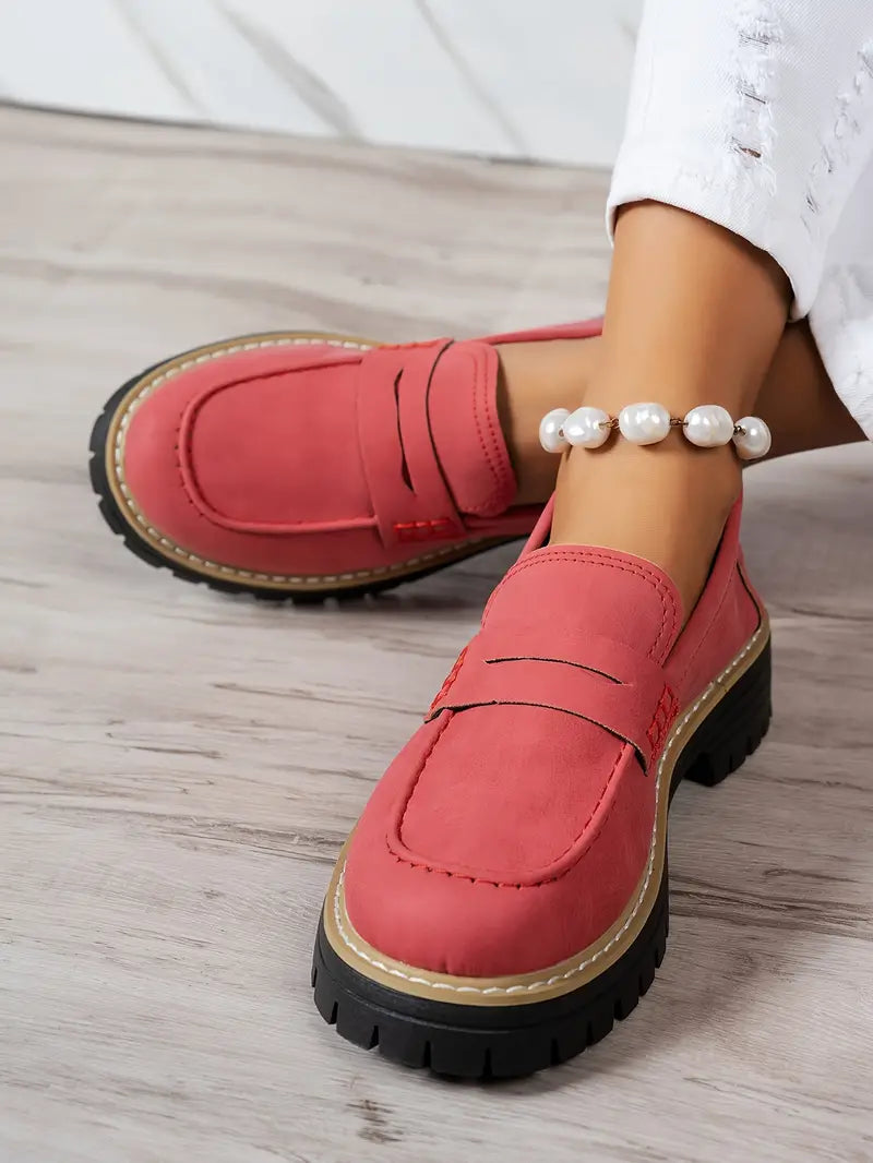 Mocassins rouge corail pour femme printemps été 2025, avec semelle crantée noire, style tendance casual chic, disponibles sur reinemonde.com, portés avec jean blanc et bracelet de cheville perles.
